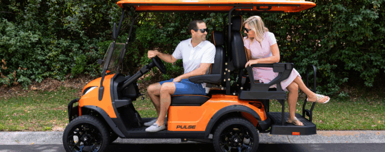 Couple sitting in orange 4 seater Pulse golf cart